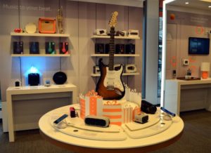 Guitar on a table surrounded by Bluetooth speakers.